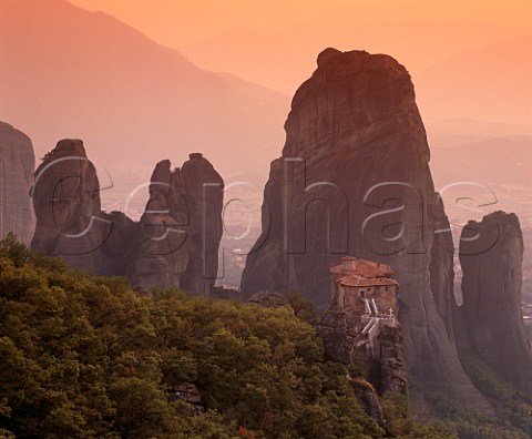 Dusk falls over Roussano Monastery amongst the rock pinnacles of the Meteora with the Plain of Thessaly beyond   Greece