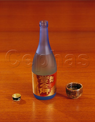 Bottle of Ohshu Ohgonkyou Japanese sake produced by   Iwateshu with traditional pottery cup ochoko