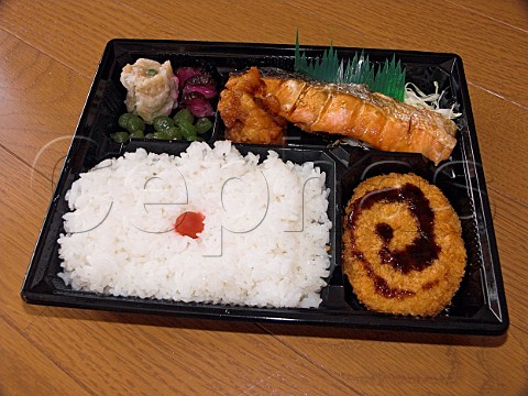 Japanese Bento packed lunch consisting of grilled   salmon deepfried chicken boiled rice potato   croquette and pickles