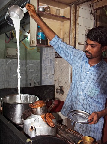 Young man making Indian tea the milk and the water   is boiled together Chennai Madras India