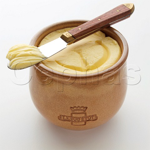 A stoneware pot of butter with a knife on top