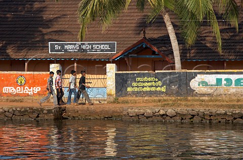 Young boys walking past St Marys High School on the banks of the Kuttanad the backwaters of Kerala known as the Venice of the East Kerala India