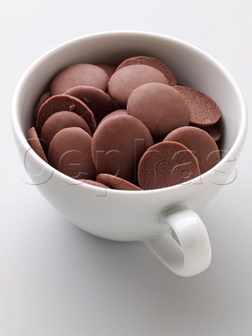 A white cup full of chocolate buttons