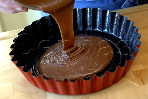Pouring chocolate cake mix into a baking tin