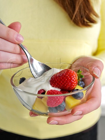 Woman eating fruit salad with yoghurt