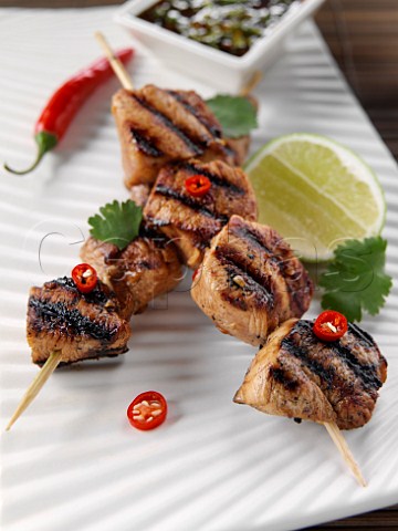 Two chicken kebabs on skewers with dipping sauce