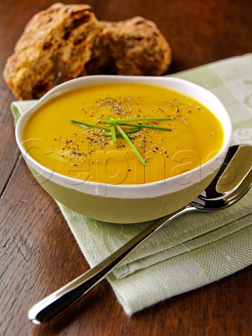 Bowl of pumpkin soup with brown bread rolls