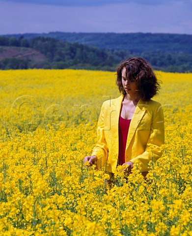 Young woman in a flowering field of oil seed rape