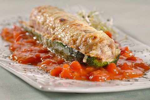 Courgette stuffed with cheese topped sausage meat on a bed of chopped tomatoes