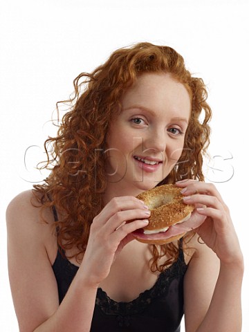 Young woman at breakfast table bagel with ham and cream cheese