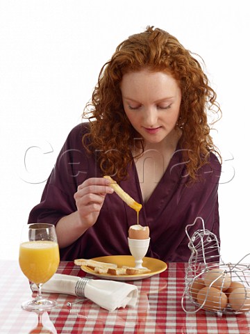 Young woman at breakfast table boiled eggs with white bread soldiers glass of orange juice