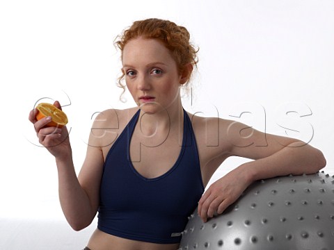 Young woman with half an orange after workout in a gym
