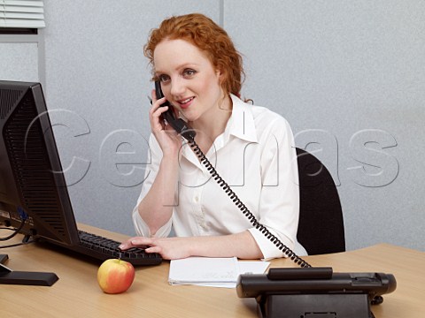 Young woman at her office desk talking on telephone
