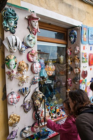 Tourists looking at face masks outside a souvenier shop window Murano Venice Italy