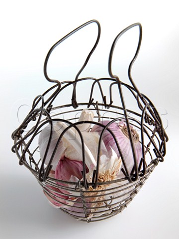 Garlic in a wire basket on a white background