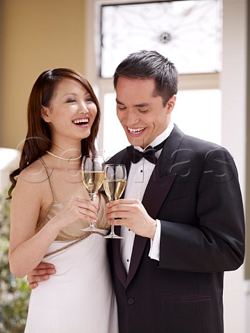 Young oriental couple in formal dress drinking wine