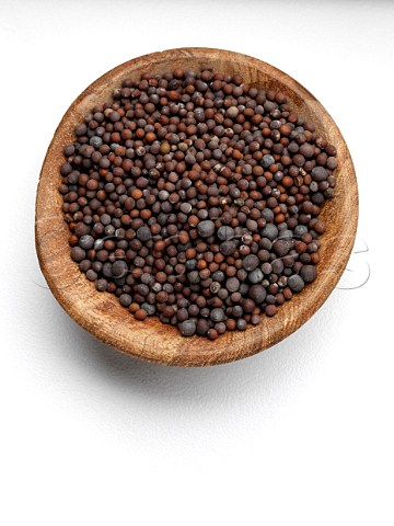 Wooden bowl of mustard seed on a white background