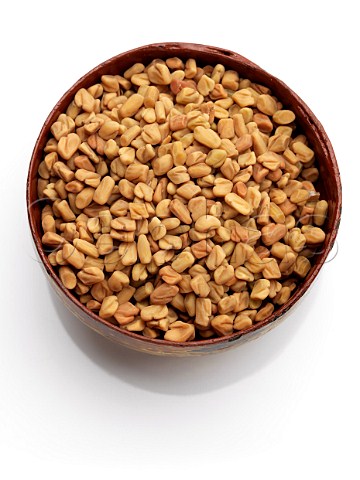 A wooden bowl of fenugreek on a white background