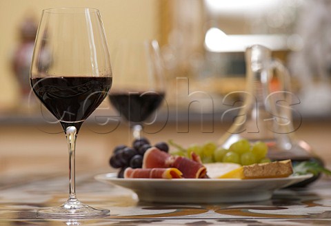 Glasses of red Bordeaux wine with plate of grapes ham and cheese