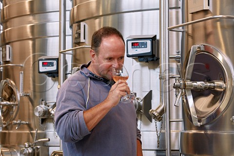 Mark Driver owner tasting Pinot Meunier from tank in the winery of Rathfinny Wine Estate Alfriston Sussex England