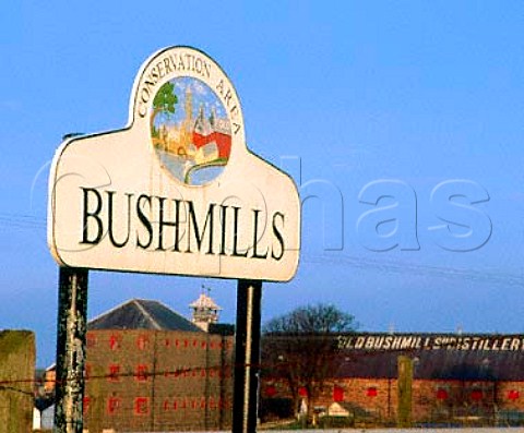 Sign at entrance to the town of Bushmills with the   Old Bushmills Whisky Distillery in the background   CoAntrim Northern Ireland