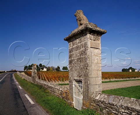 The D2 road passing autumnal vineyard of Chteau Latour house and pigeonnier on  right with Chteau PichonLonguevilleComtessedeLalande on left The monuments in the wall signify the end of Chteau LovillelasCases in the commune of StJulien and the start of Latour in Pauillac Gironde France    Mdoc  Bordeaux