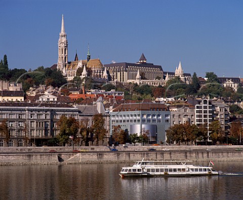 View across the Danube from Pest to Buda with tourist boat on the river on the hill are St Matthias Church Hilton Hotel and Fishermans Bastion  Budapest Hungary