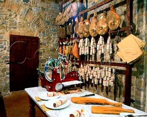 Salamis for tasting with hams salamis and other   cured meats hanging up behind Macelleria Stiaccini   Castellina in Chianti Tuscany Italy