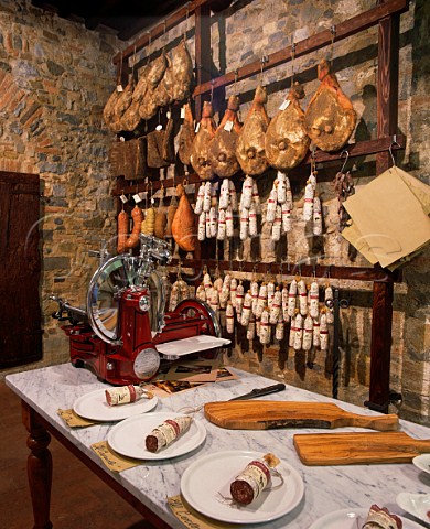 Different salami for tasting with hams salami and other cured meats hanging up behind Macelleria Stiaccini Castellina in Chianti Tuscany Italy