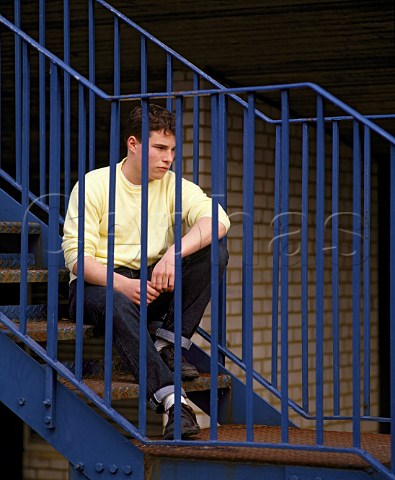 Teenage boy sitting on steps behind railings
