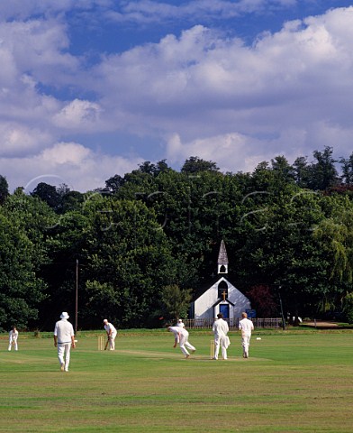 Cricket on the village green with StGeorges Church beyond West End near Esher Surrey England