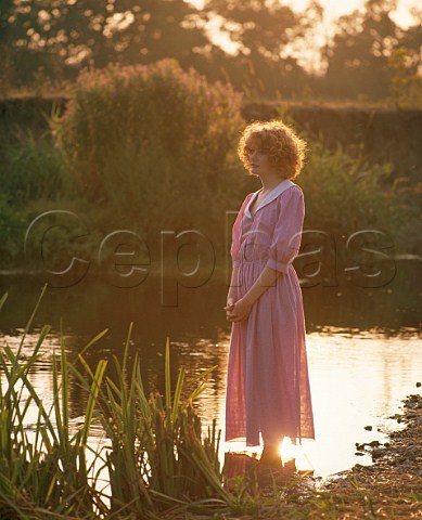 Young woman 16 standing in water at edge of river