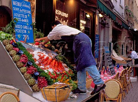 Preparing a fresh fish and vegetable display outside  a restaurant on Petite rue des Bouchers near the  Grand Place Brussels