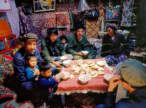Family eating their evening meal of rice soup and   bread in a Mongolian yurt Xinjiang Province China