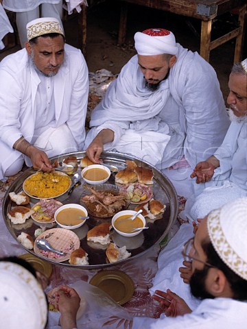 Group of Shiite muslims at their midday meal of pilau  rice chicken bread etc during a festival   Karachi Pakistan