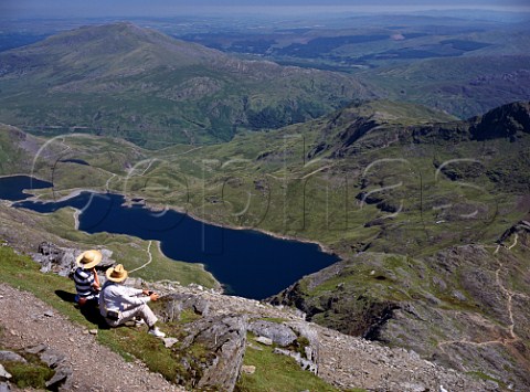 Walkers relaxing at the summit of Mount Snowdon with Llyn Llydaw reservoir below    Snowdonia National Park Wales