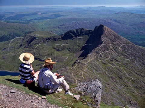 Walkers relaxing at the summit of Mount Snowdon looking down on the ridge of Y Lliwedd   Snowdonia National Park Wales