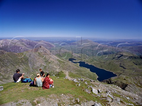 Walkers relaxing at the summit of Mount Snowdon with Llyn Llydaw reservoir below  Snowdonia National Park Wales