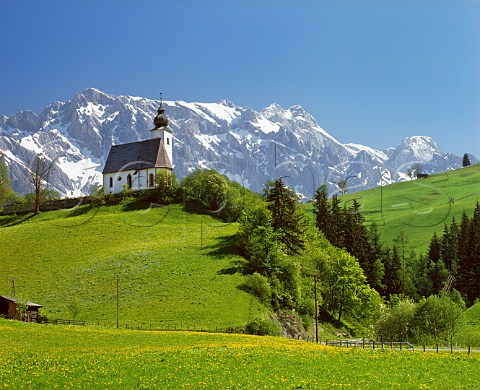 Church above spring meadow with Hochkonig mountain beyond Salzburgerland Austria 
