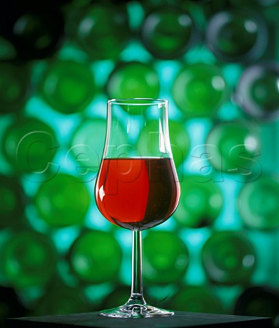 Glass of red wine in front of bottles