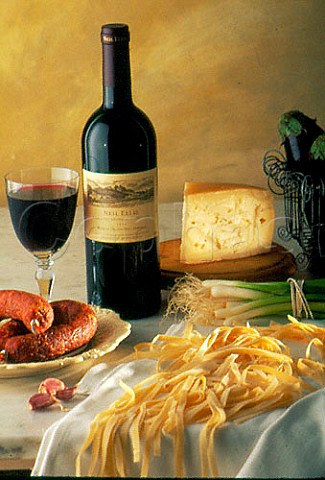 Sausage cheese and pasta with a glass  and bottle of Neil Ellis Cabernet  Sauvignon  Merlot South Africa