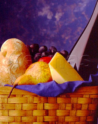 Picnic basket with bread cheese grapes pear and a   bottle of wine