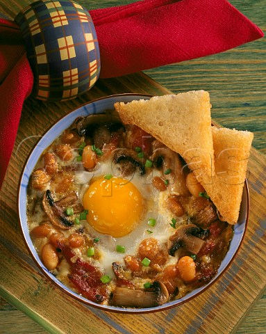 Baked breakfast with egg bacon mushrooms baked  beans and fried bread triangles