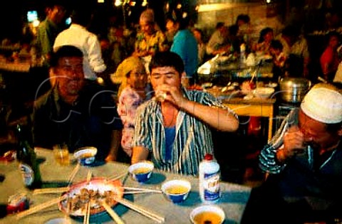 Drinking a chaser of fiery rice wine at   the night market in Turpan   Xinjiang province China