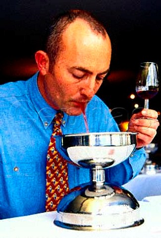 Wine taster spitting into a spittoon