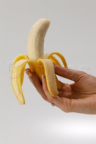 Womans hand holding peeled banana