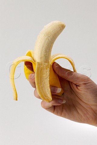 Womans hand holding peeled banana