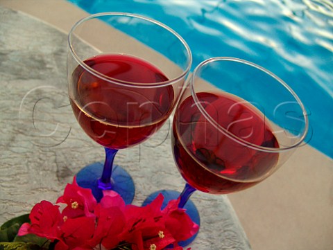 Red wine glasses  sprig of Bougainvillea on   poolside table  Florida USA