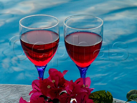 Red wine glasses  sprig of Bougainvillea on   poolside table  Florida USA