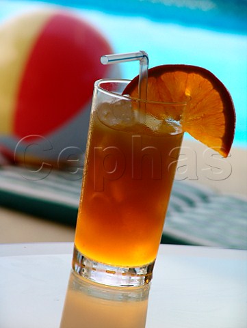 Glass of iced orange juice with pool  beach ball   behind Florida USA